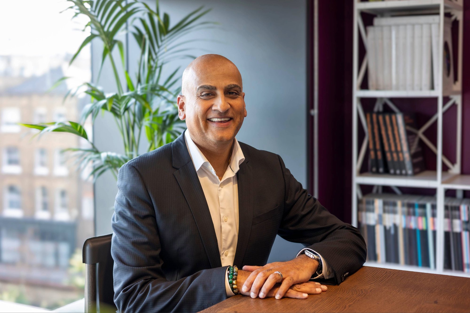 Nilesh Parmar sitting at table, smiling to camera